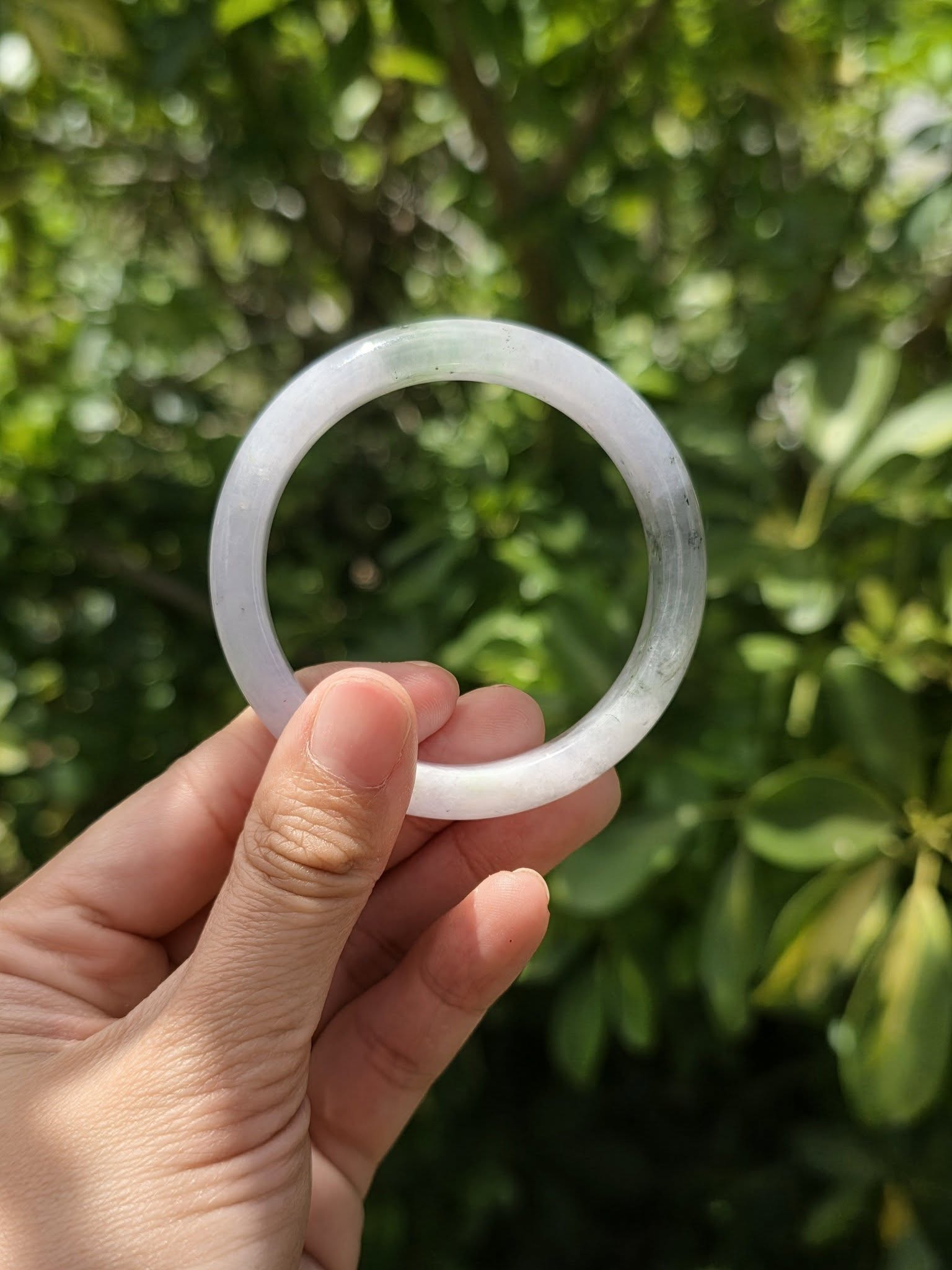 Lavender jade bangle held in hand